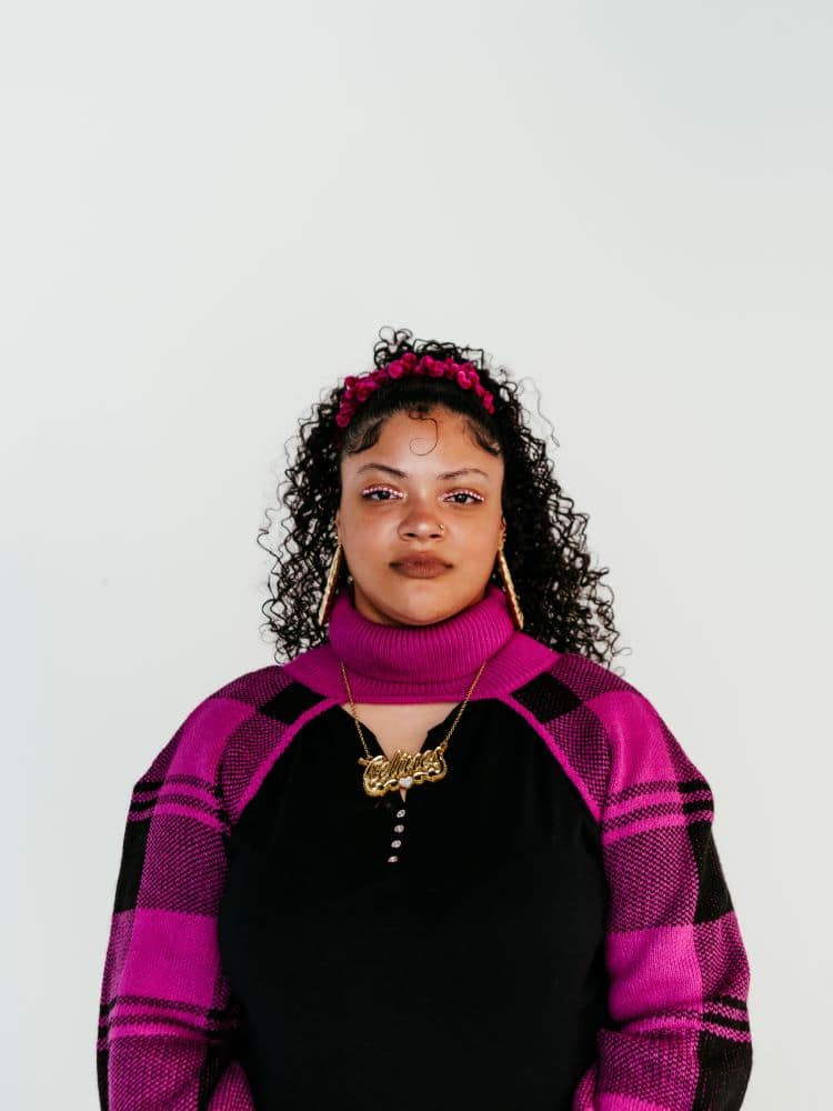 A woman with curly hair wearing a pink striped scarf.