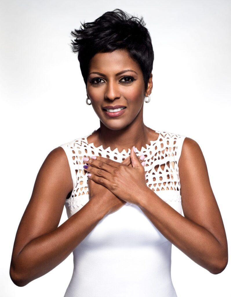 Tamron Hall in a white dress with hands over her heart