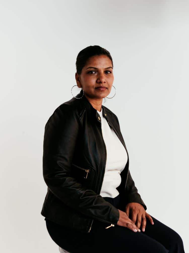 A woman wearing a white shirt and a leather jacket.